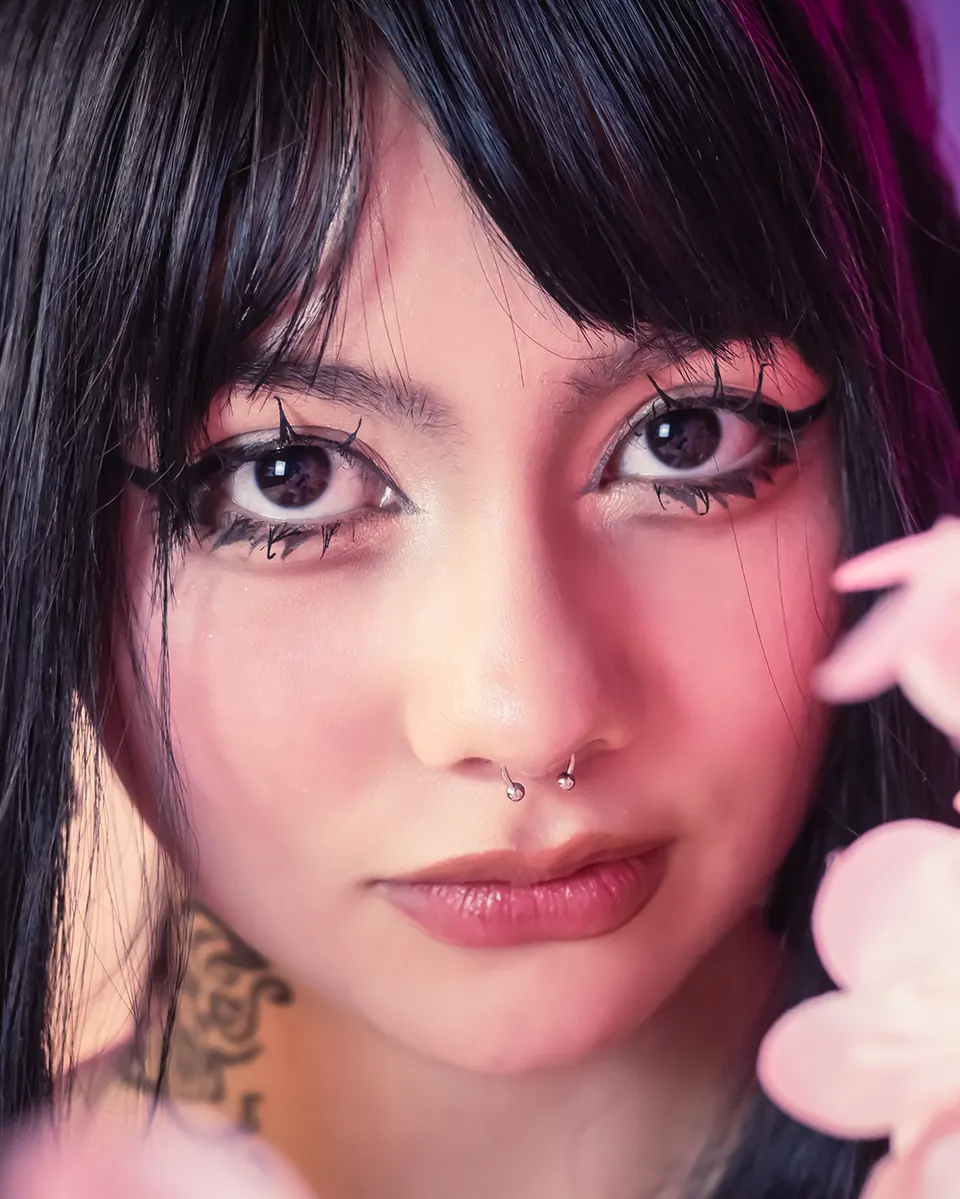 Modelo de Crudo Studio en un room con luz magenta y flores rosadas