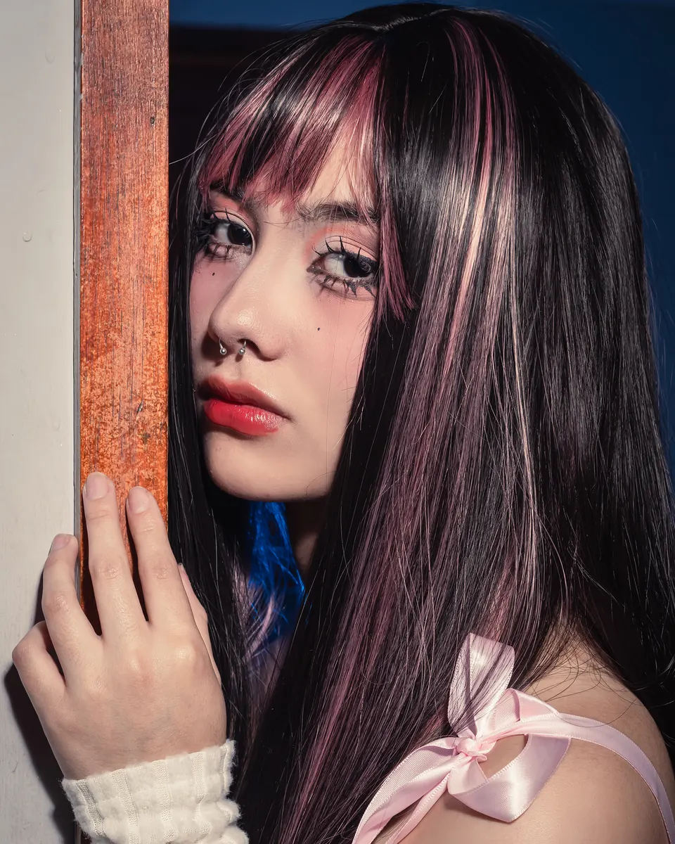 Retrato de una modelo en penumbra azul junto a una puerta de madera