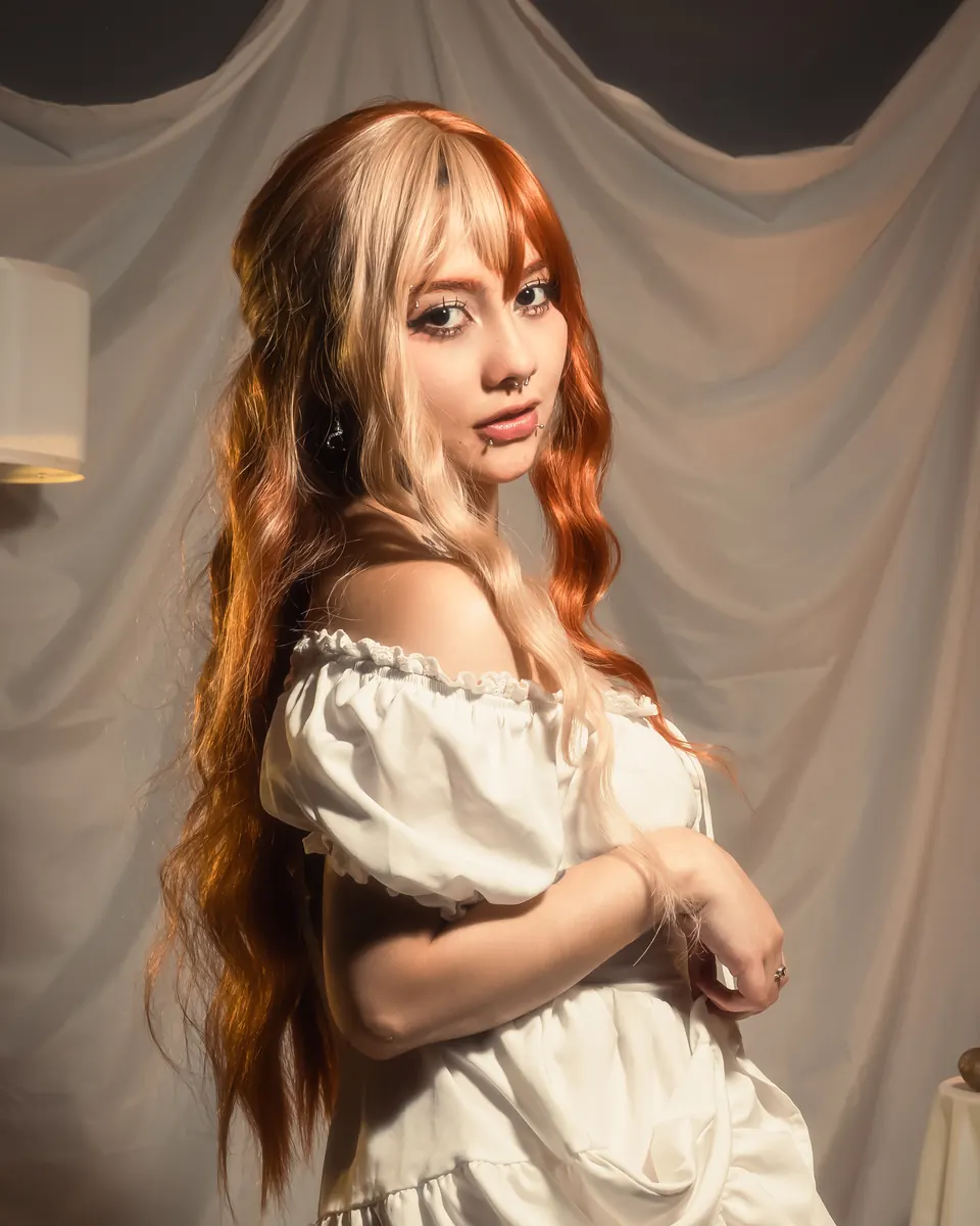 Modelo de pie con vestido blanco frente a cortina crema