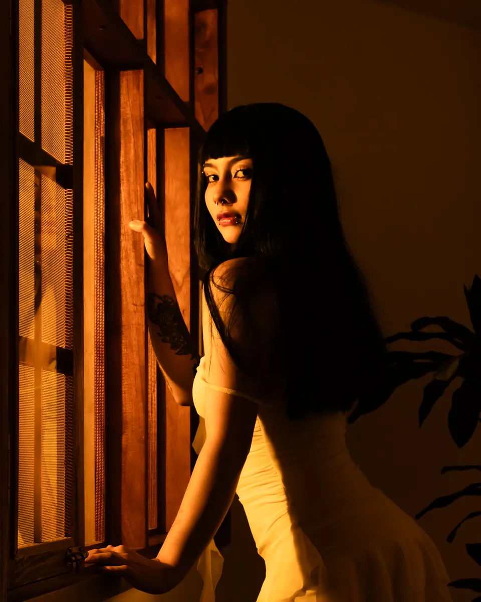 Modelo junto a una ventana de madera con luz dorada