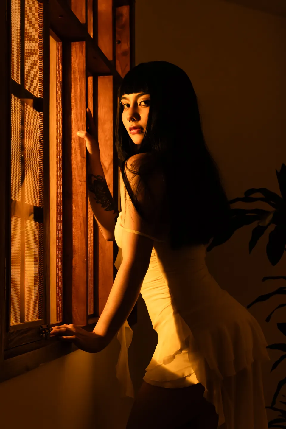 Modelo junto a una ventana de madera con luz dorada