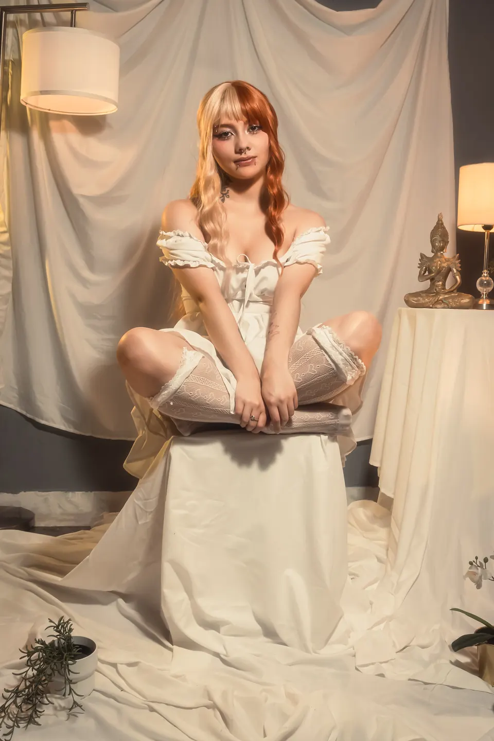 Modelo sentada en un set crema con lámparas y telas